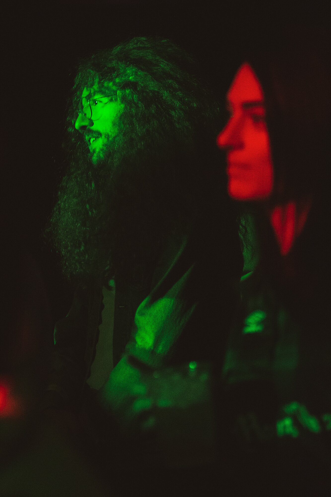 Two people seen in profile, one under green light, the other in red.