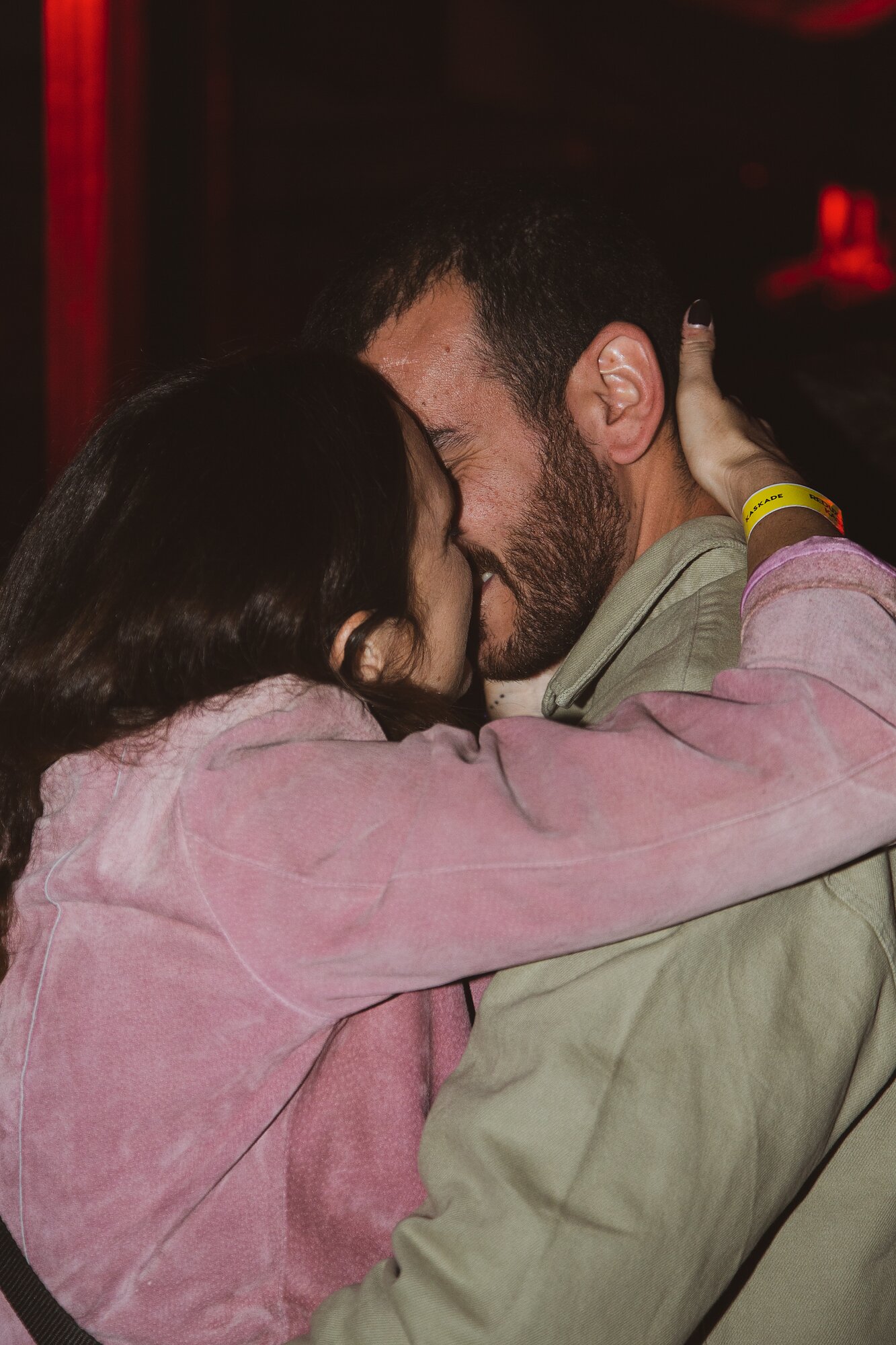 A close-up of two people smiling and embracing for a kiss.