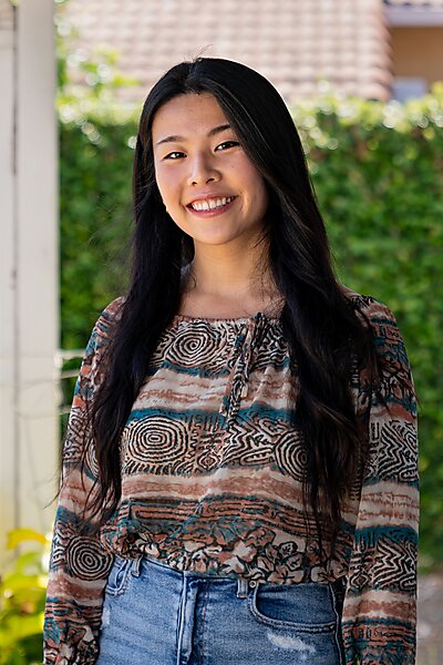 Portrait of an Asian woman with long black hair smiling outdoors