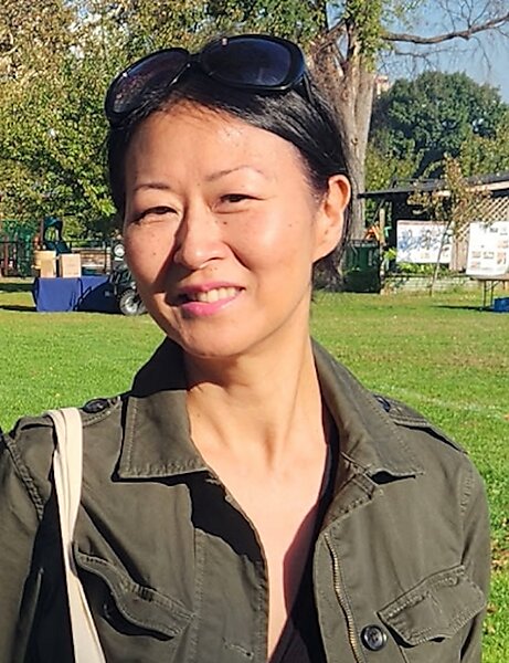 Portrait of an Asian woman outdoors smiling with sunglasses on the top of her head