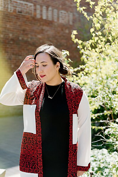 portrait of Nadia Tahoun outdoors looking downward with a hand to her face