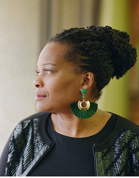 An African American woman with green earring in the side profile