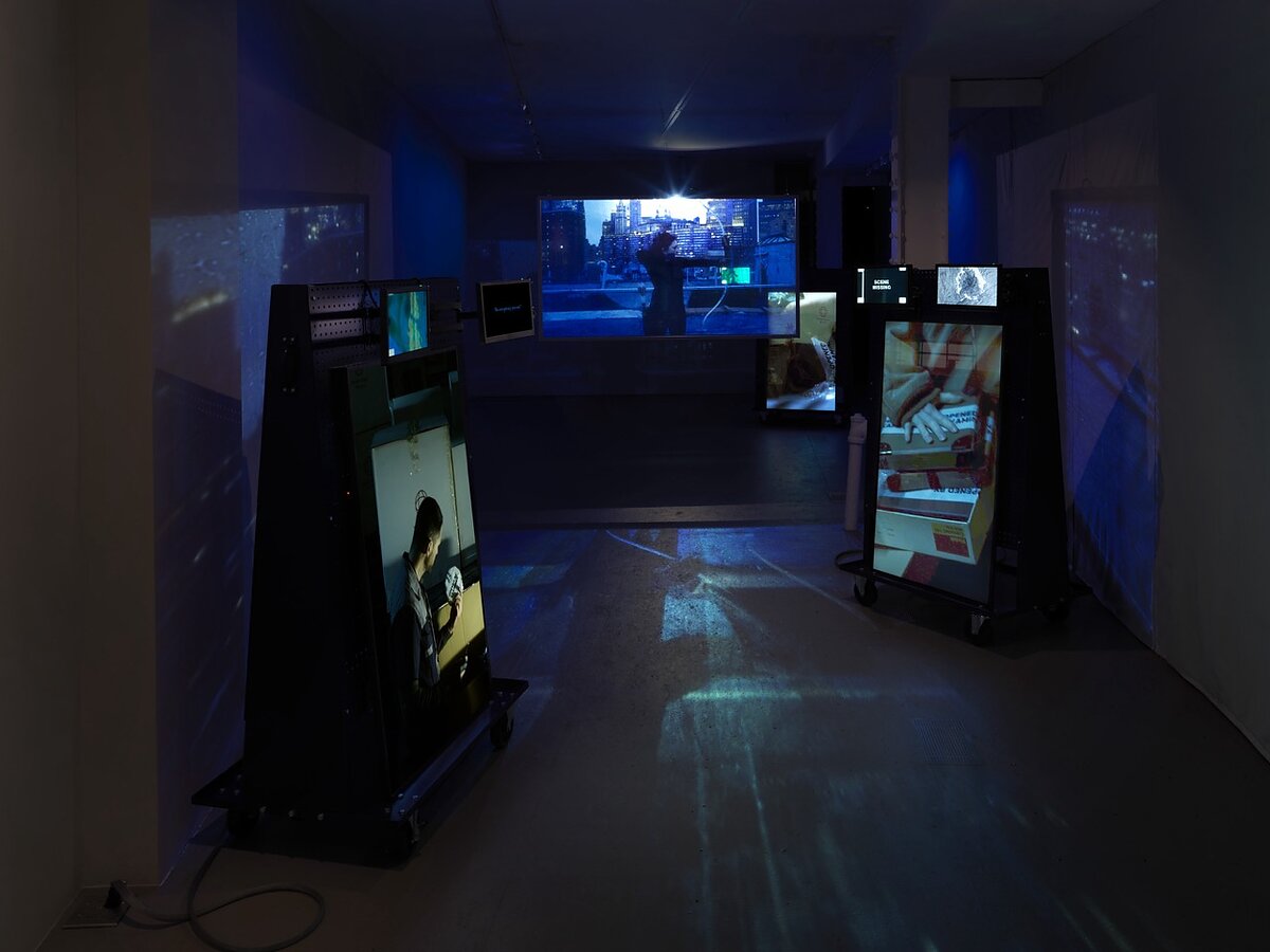 A gallery space showing various screens, some vertically oriented and others horizontal.