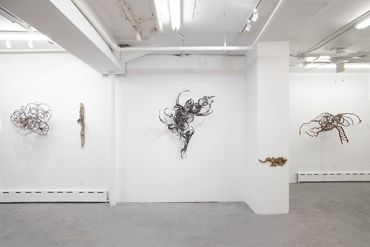 A gallery wall features a series of metallic and wooden sculptures. 