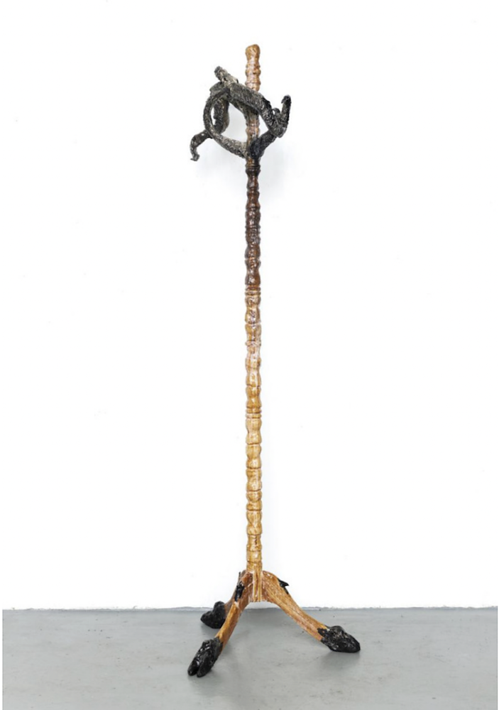 A wooden coatrack with black hooves for its feet and sheep antlers for coat hooks. 