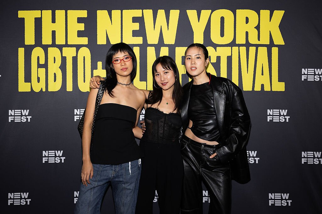 Three east Asian women pose in front of a step and repeat that says "The New York LGBTQ+ Film Festival" and "New Fest". 