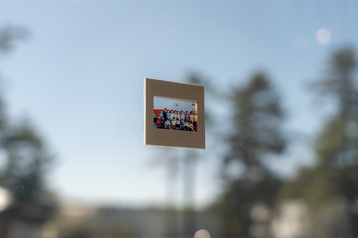 A small projector slide featuring children in a classroom is stuck onto a window