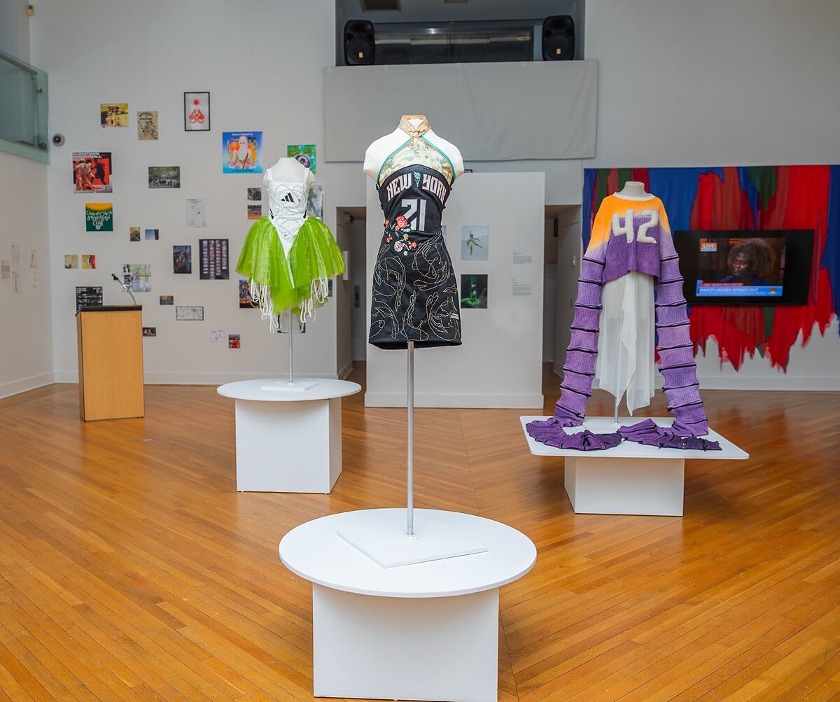 A trio of altered women's sports jerseys displayed in a gallery. 