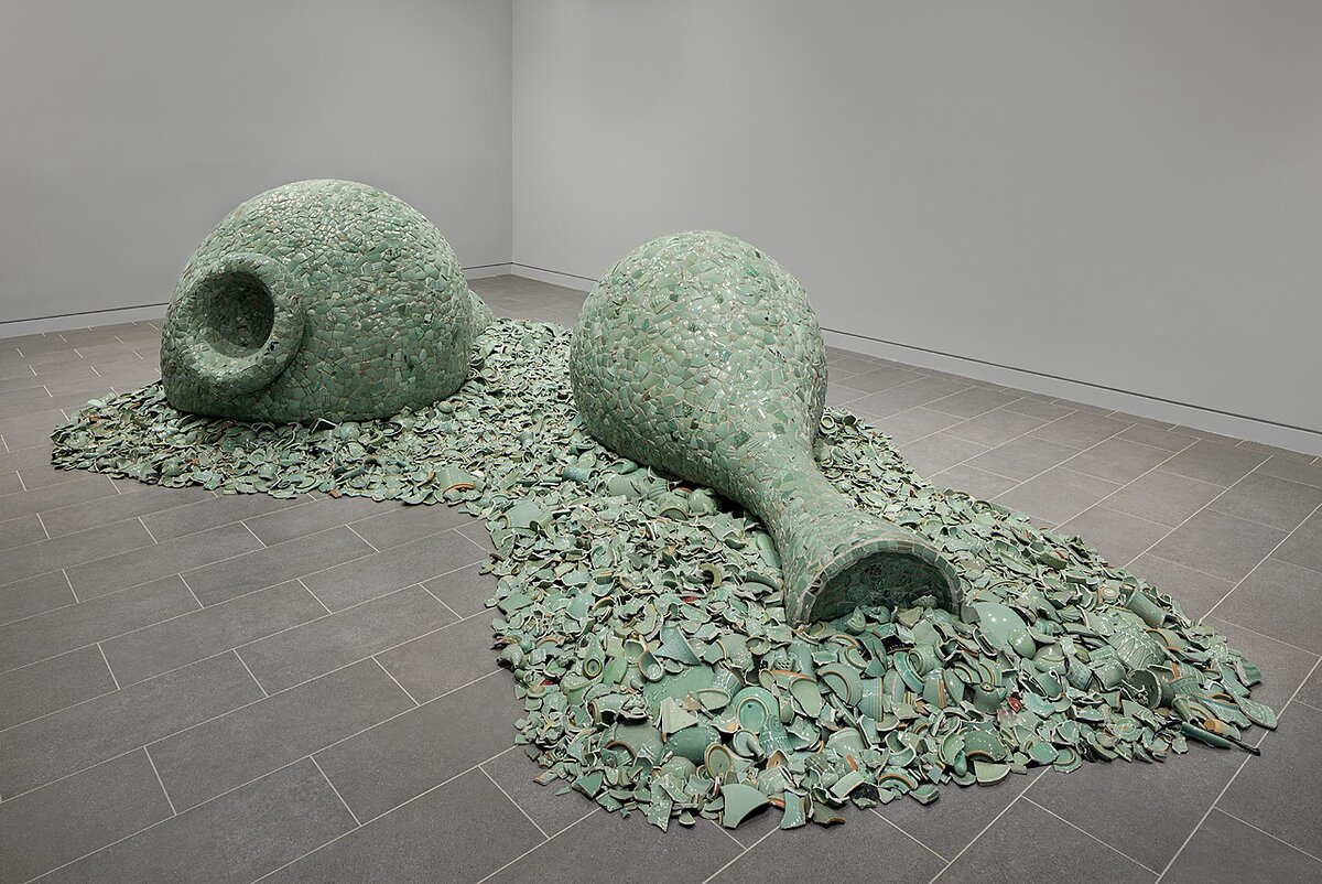 Sculptures in the shape of two giant vases made of celadon shards in a gallery.