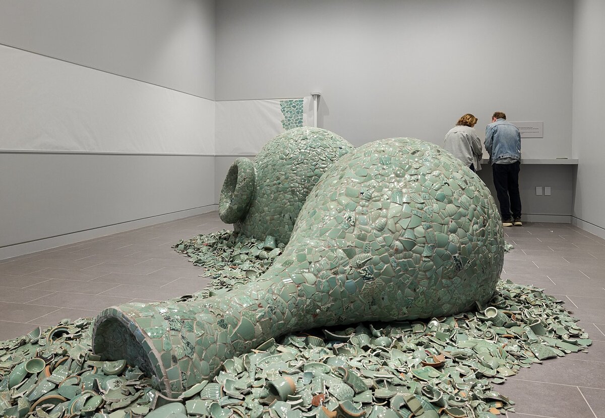 Sculptures in the shape of two giant vases made of celadon shards in a gallery.