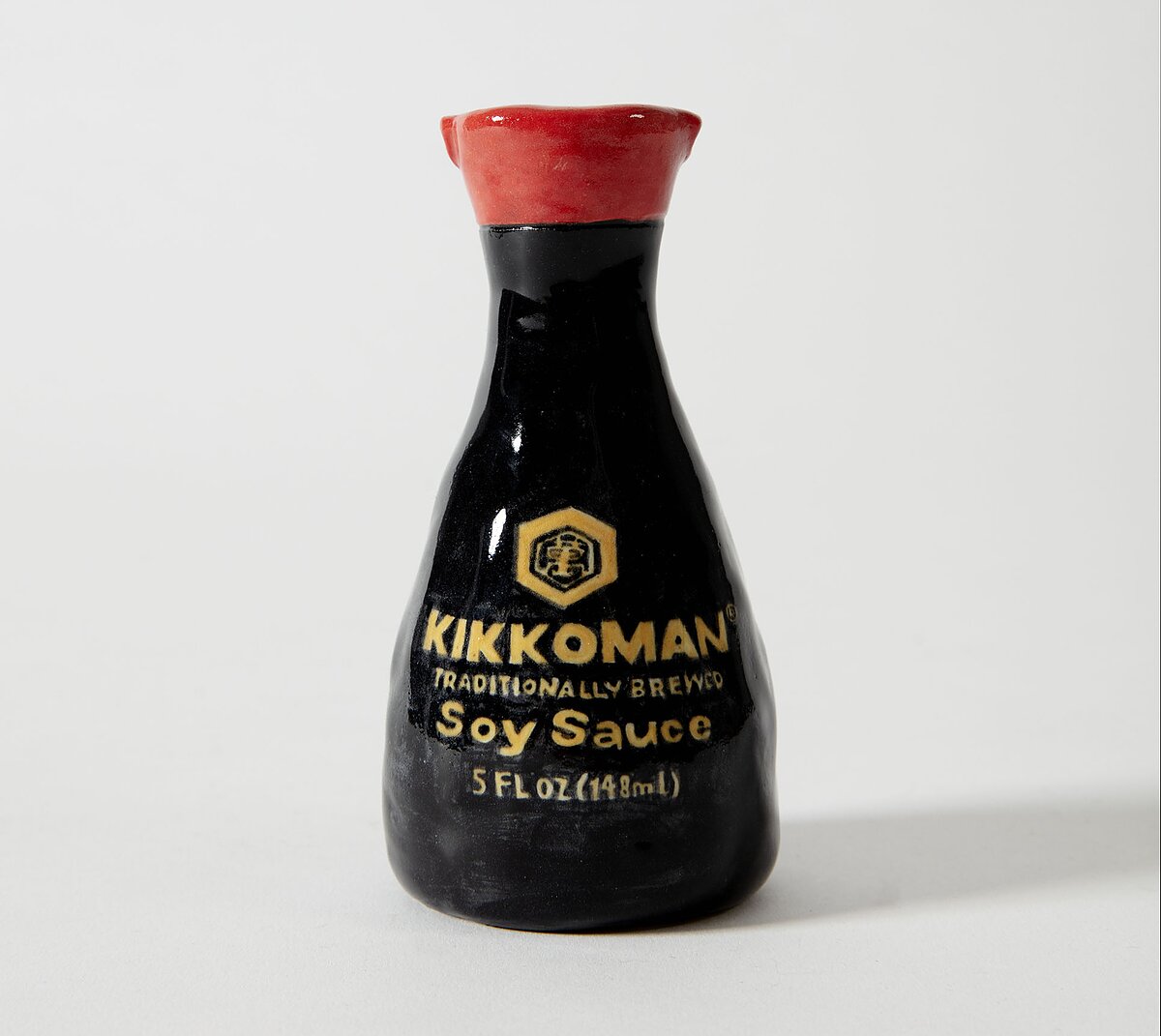 A highly detailed ceramic sculpture of a Kikkoman-brand soy sauce bottle.