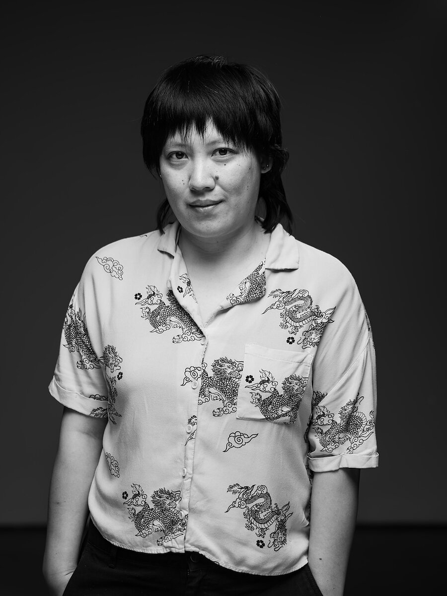 Liqing Xu, a nonbinary person with shoulder-length black hair and collared shirt with dragon patterns