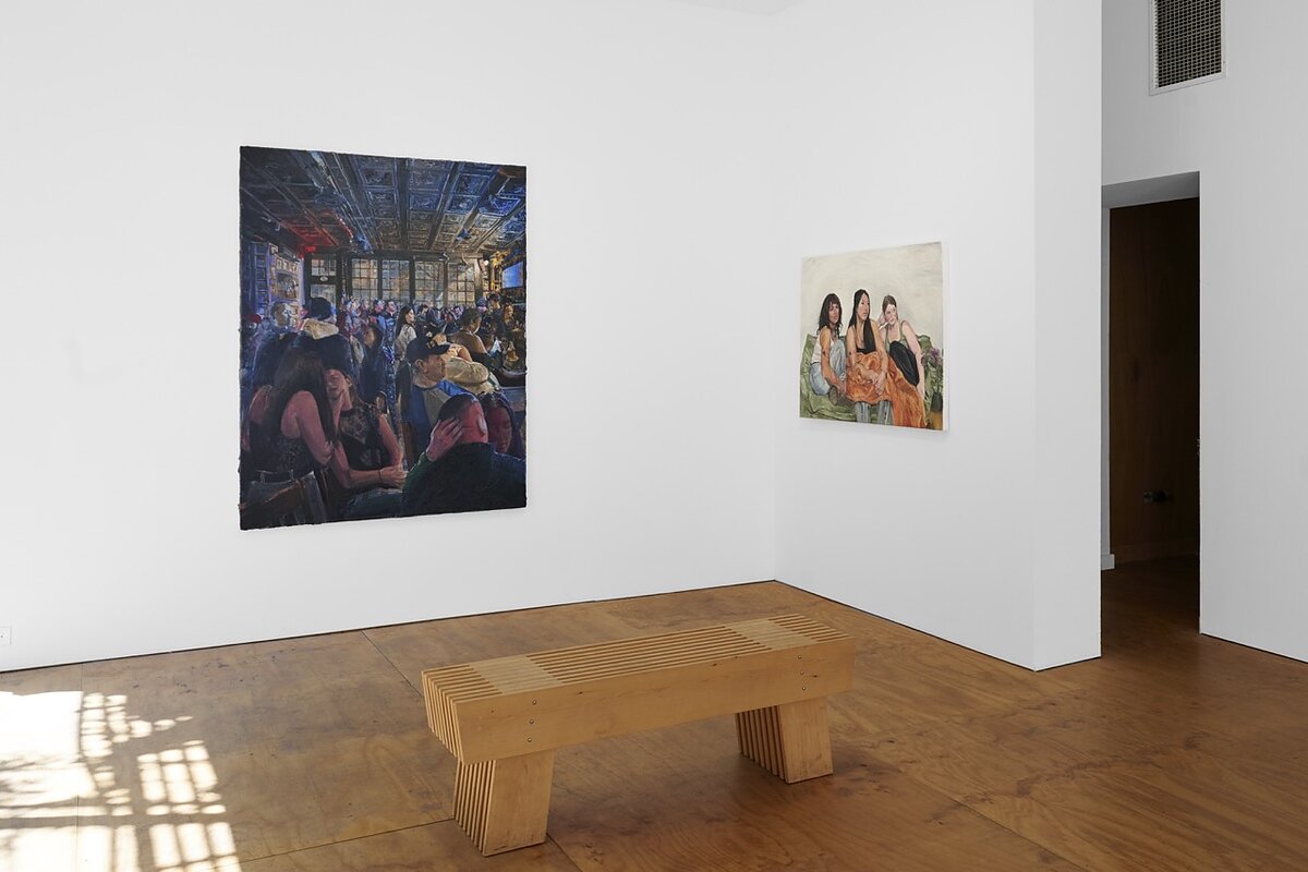 A gallery featuring two paintings hung on white walls with a wooden bench in front of them.