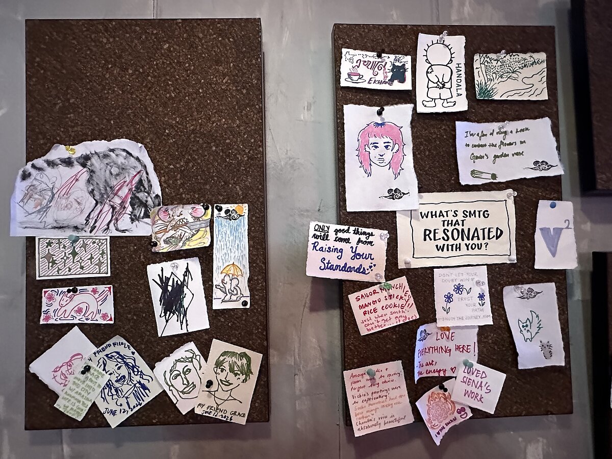 Two cork boards with drawings and notes tacked onto them. 