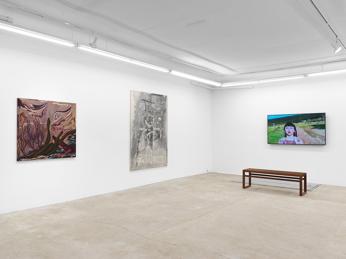 Installation image of a gallery featuring two paintings and a video work. 