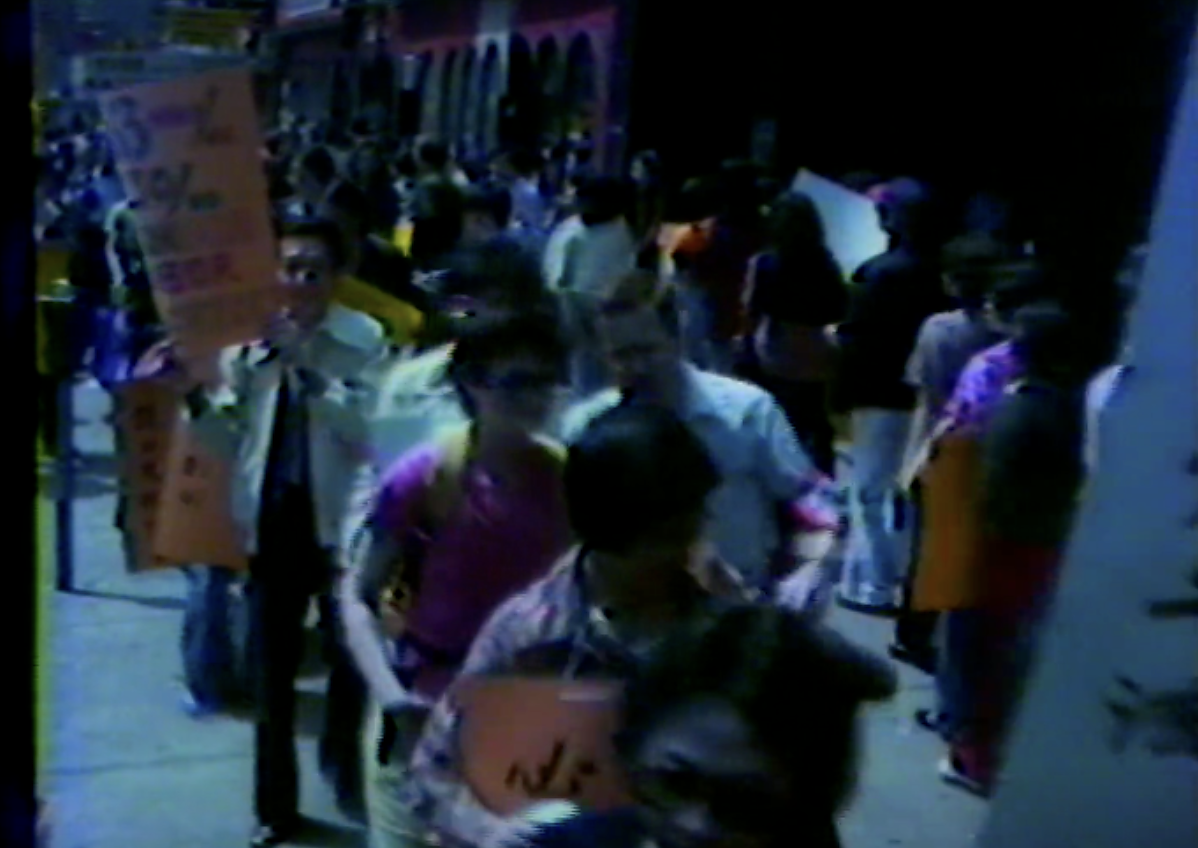 Grainy footage of a crowd of protesters. 