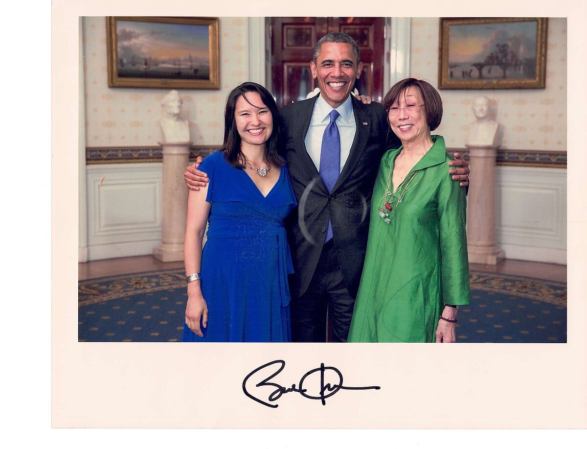 Two women and a man pose for a photograph inside a formal government building.