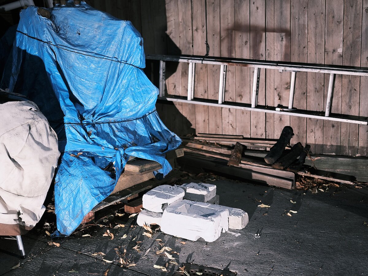 A small arrangement of concrete blocks amid a pile of junk illuminated by a spotlight at night.  