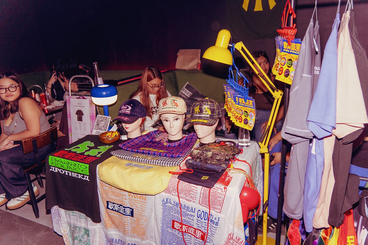 A table featuring a variety of colorful merchandise including t-shirts, bags, and hats.